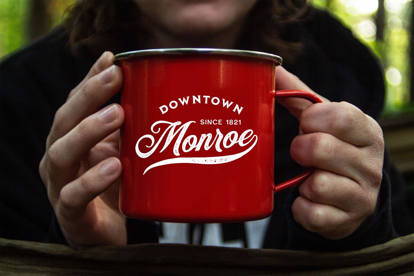 a mug that reads Downtown Monroe since 1821 in a logo format created by the UGA branding team; it is being held by a person who cannot be seen fully in the photo